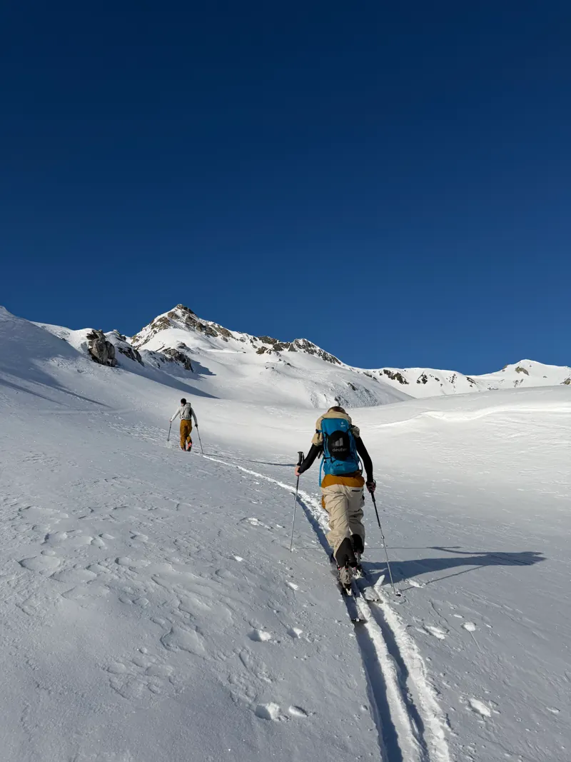Zwei Tourengeher steigen mit Fellen durch unberührten Schnee auf